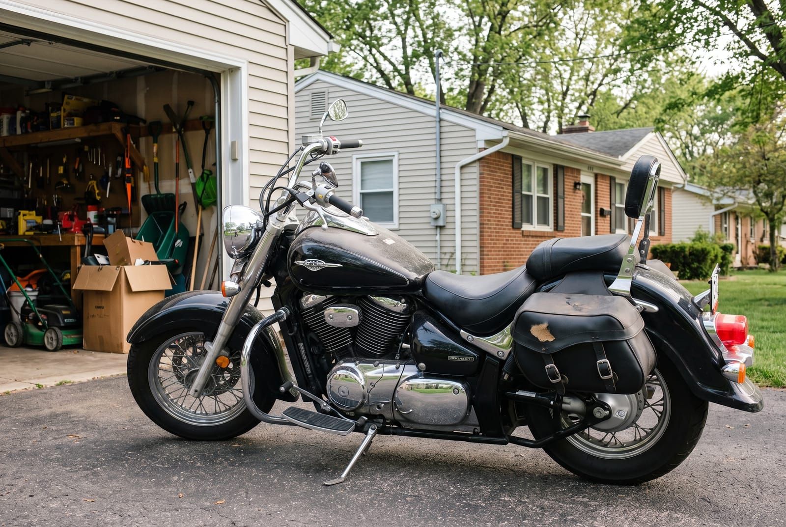 A black cruiser motorcycle parked on a driveway in front of an open garage