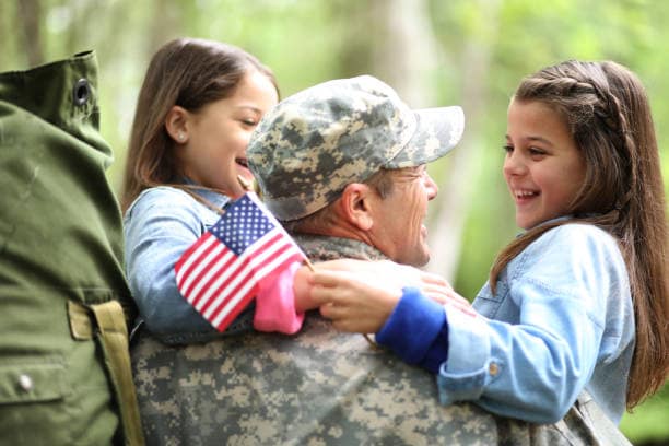 Military parent holding two smiling children