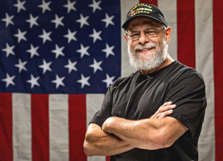 Veteran standing in front of an American flag.